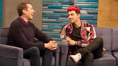 Joe Jonas Wears a Maroon and Gold Letterman Jacket With White Sneakers